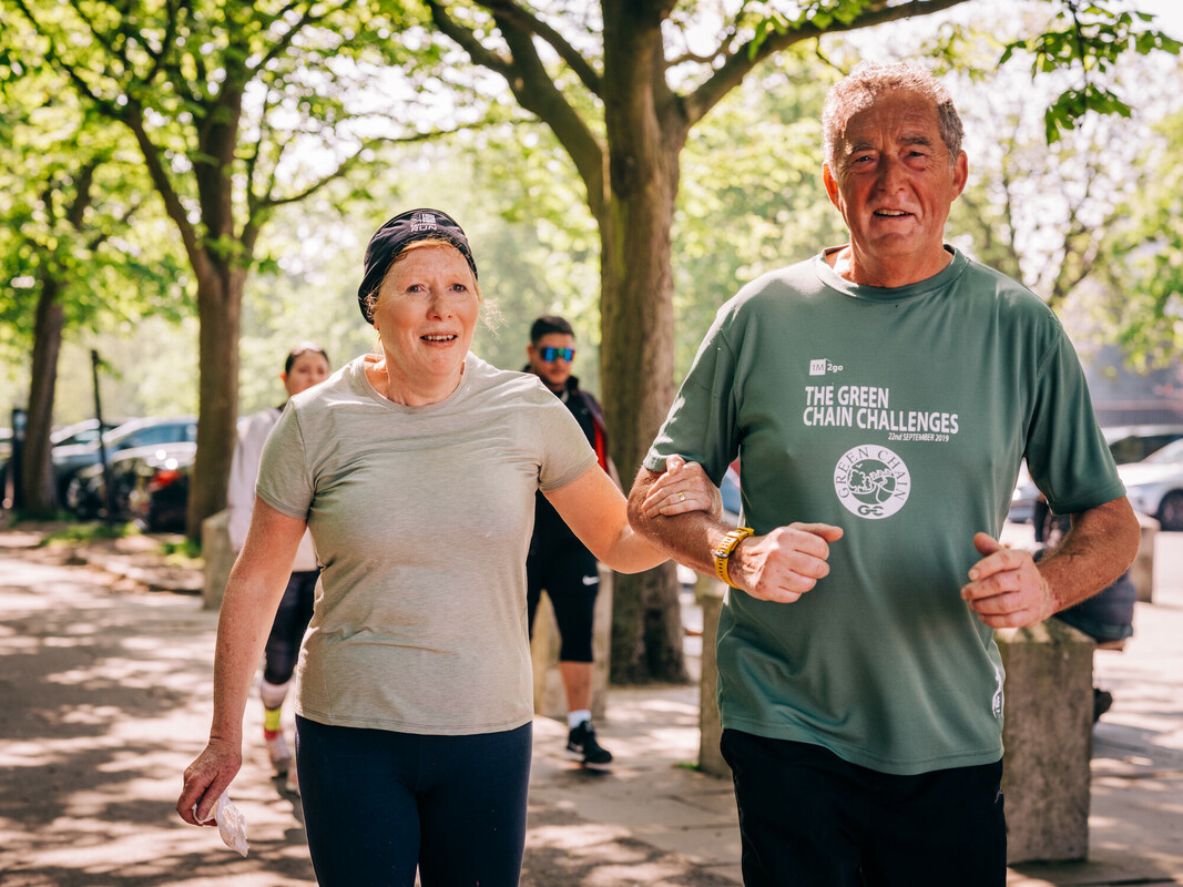 An older man and woman in running clothes linking arms