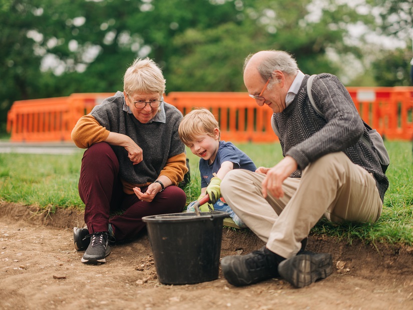 A small child looks at archaeological finds with his grandparents