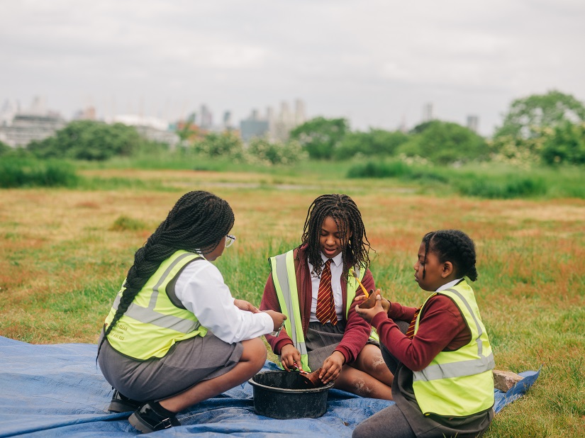 Three girls look over their finds with the view over London in the background