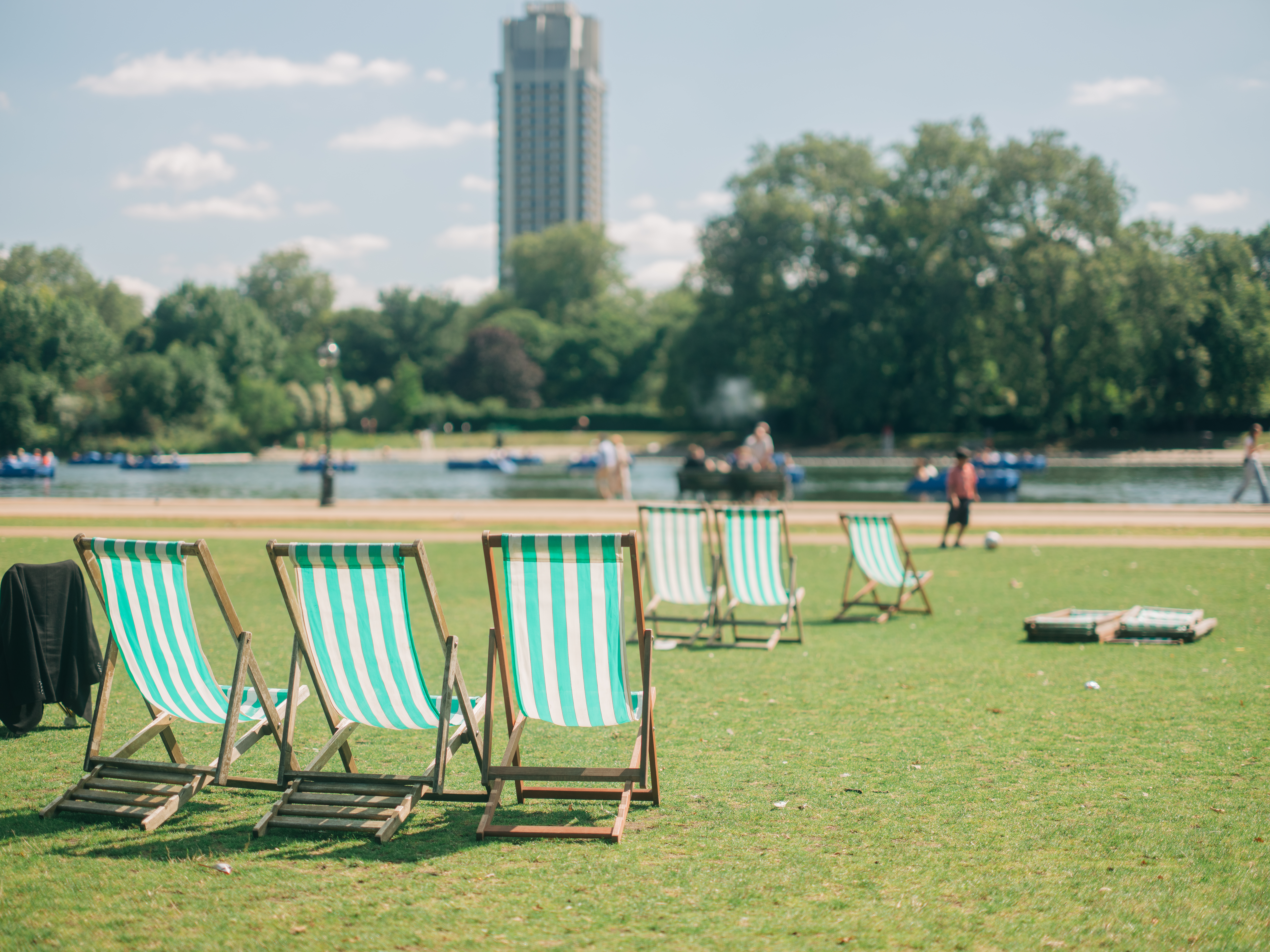Three deck chairs on a green, grassy patch near a body of water