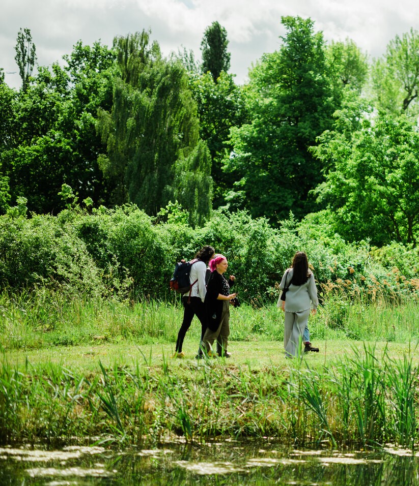 A small group of people walking beside the lake in The Regents Park