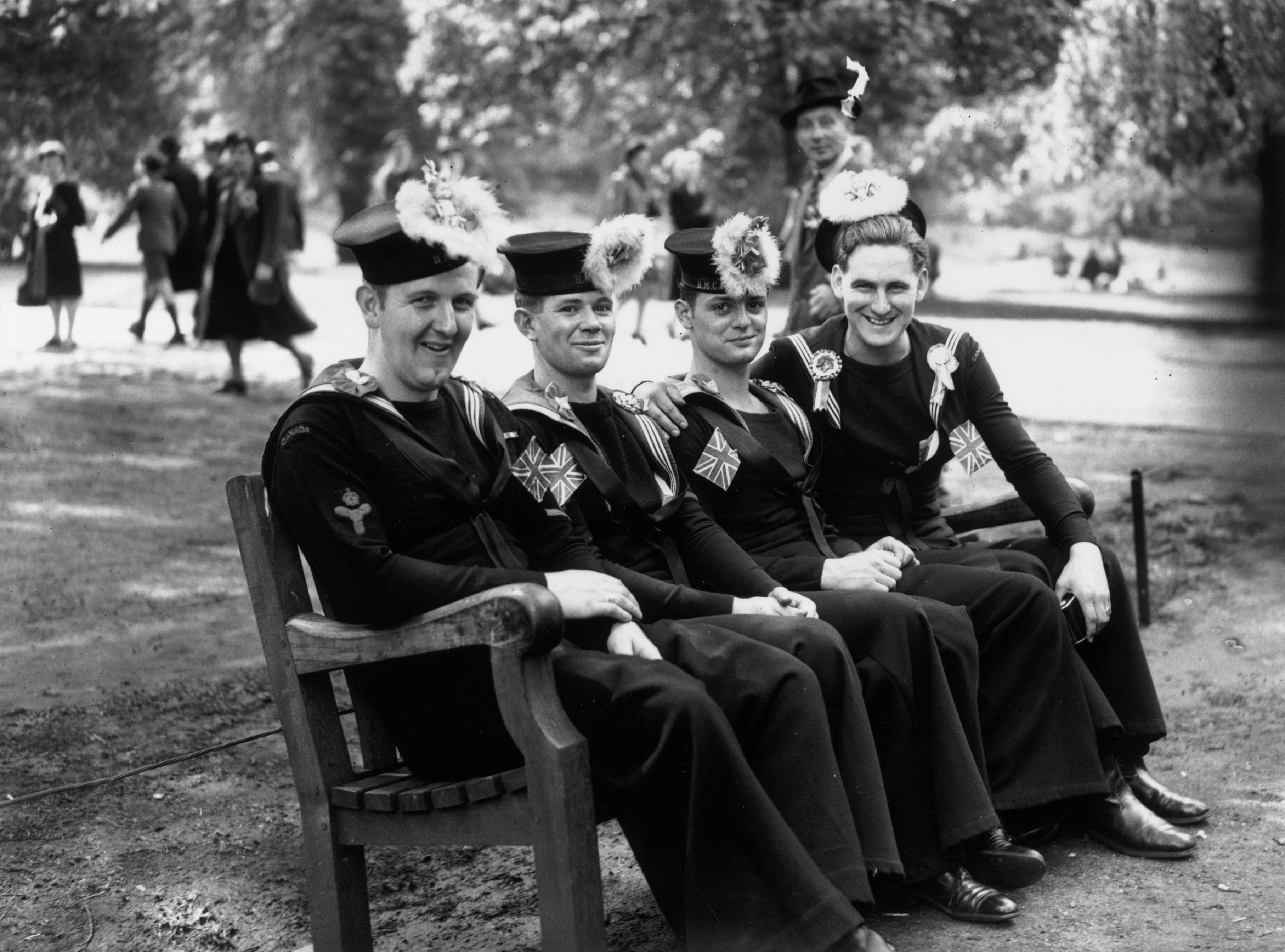 Canadian sailors sit on a bench in the park during the VE day celebrations in 1945 