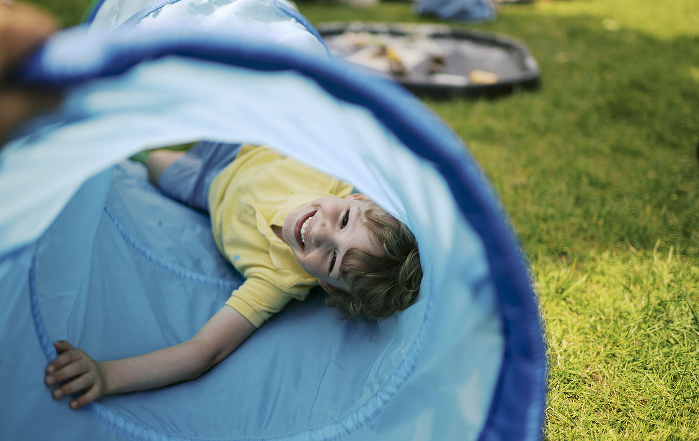 Young boy laying in a play tunnel