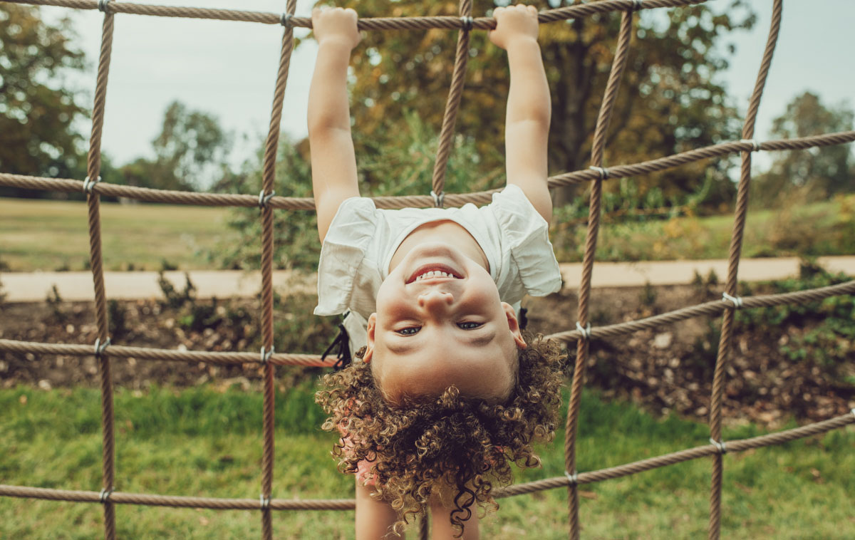 Young girl hanging upside-down on a rope net