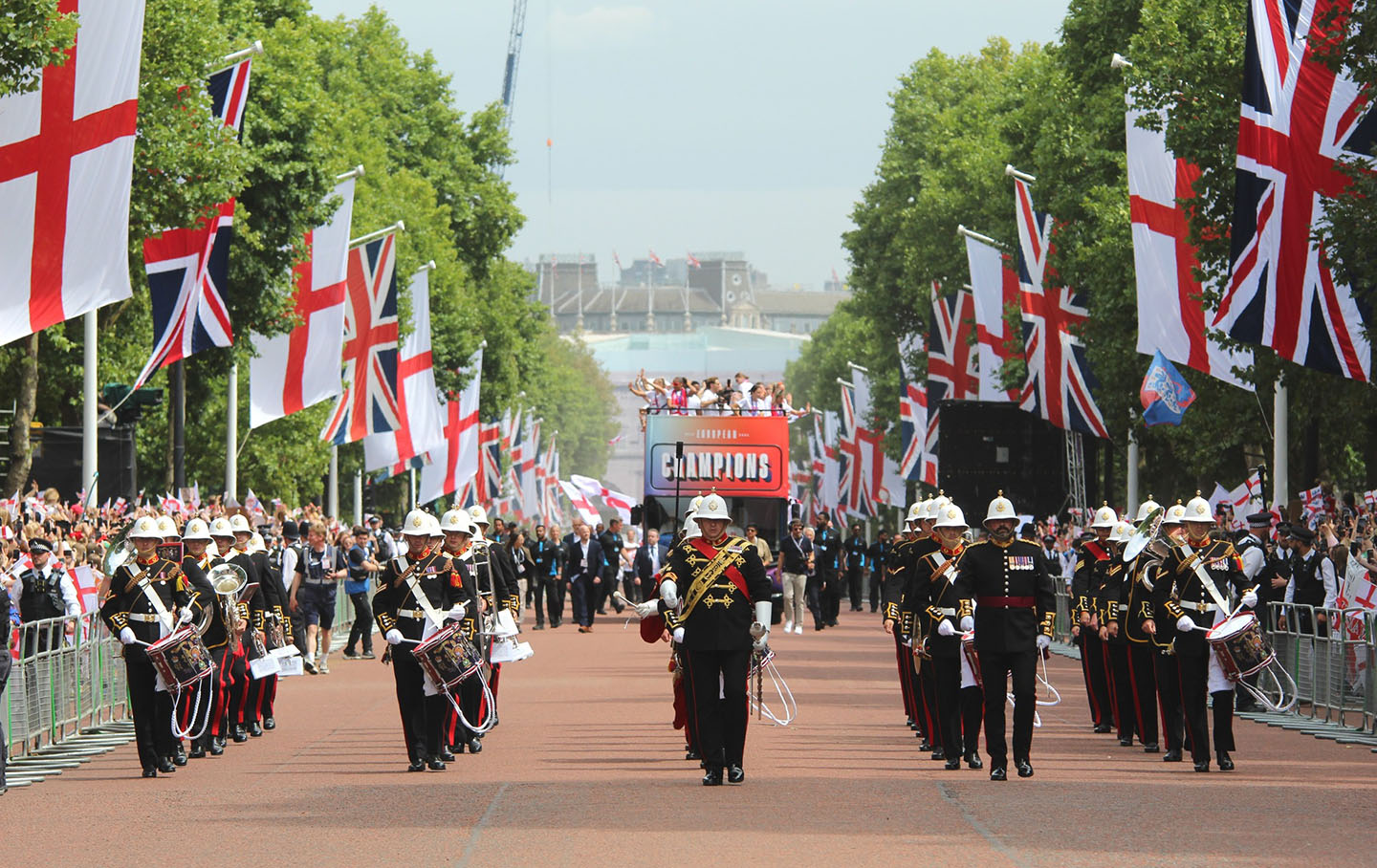 Military band leads the England Women's open-top bus down The Mall