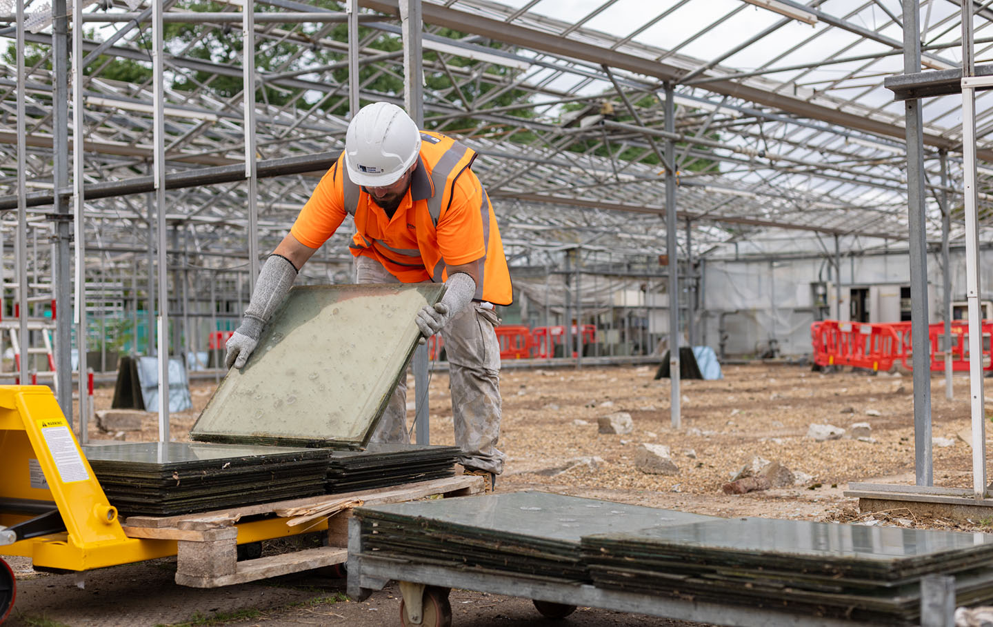Workman collecting paving slabs from the old glasshouses for reuse in the new garden