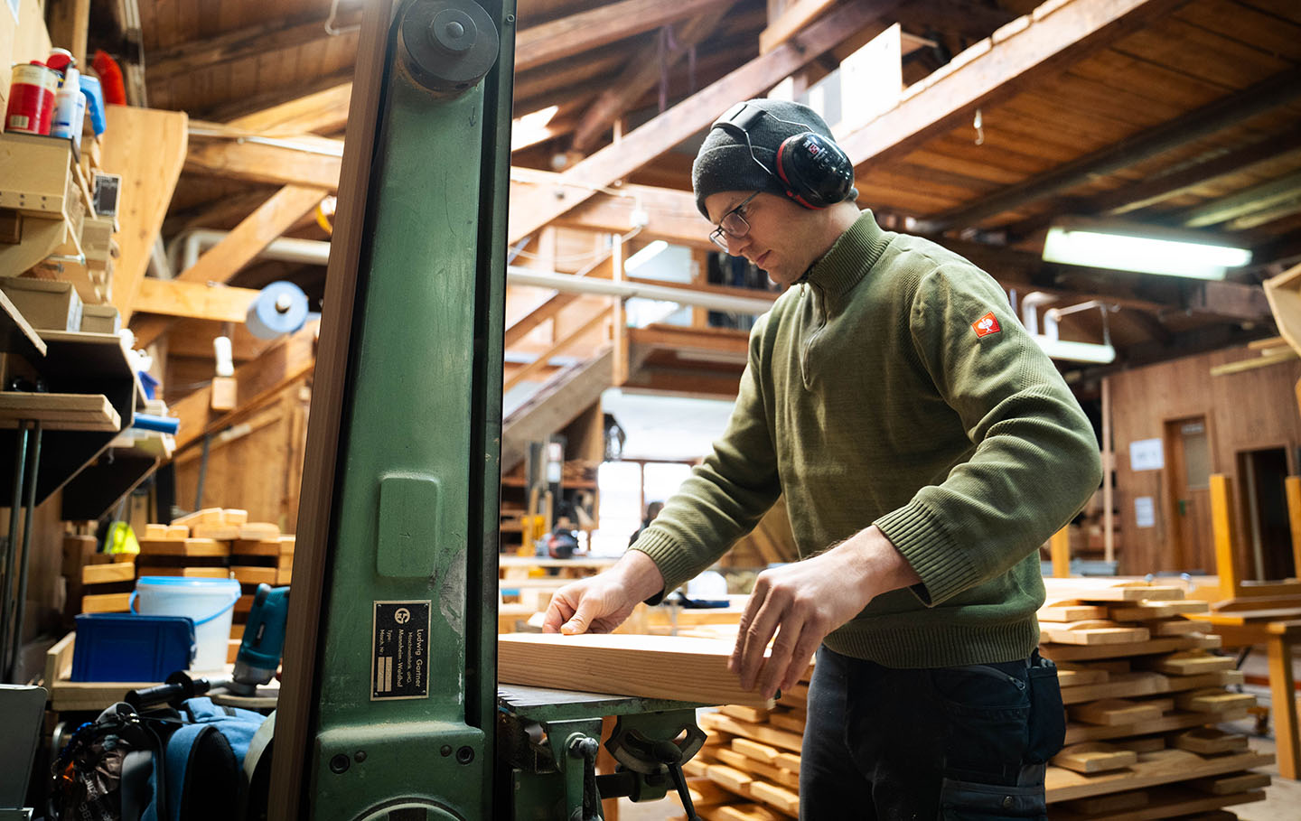 A man in a workshop sanding wood on a machine