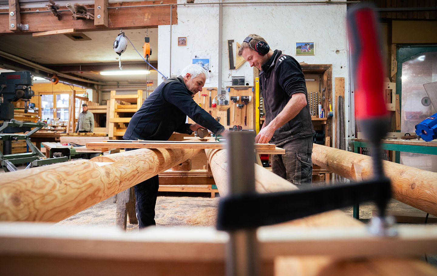Two men in a carpentry workshop working on a large timber frame