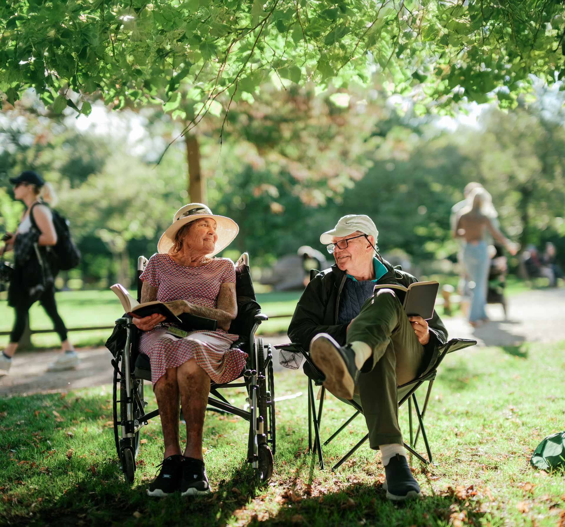 A couple reading while sitting on camping chairs in Bushy Park