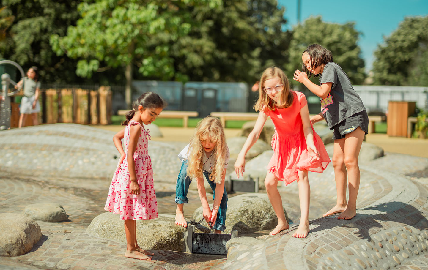 Four children playing with a playground water feature