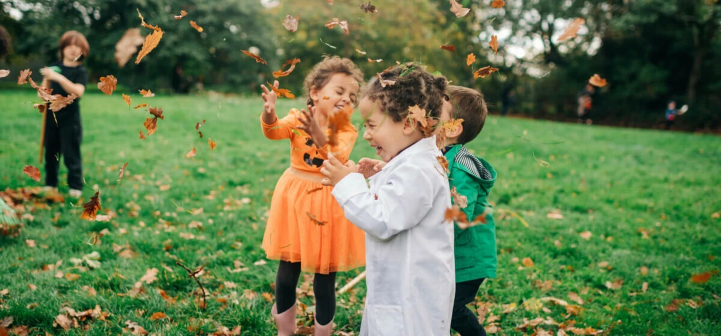 Children playing with leaves at Halloween