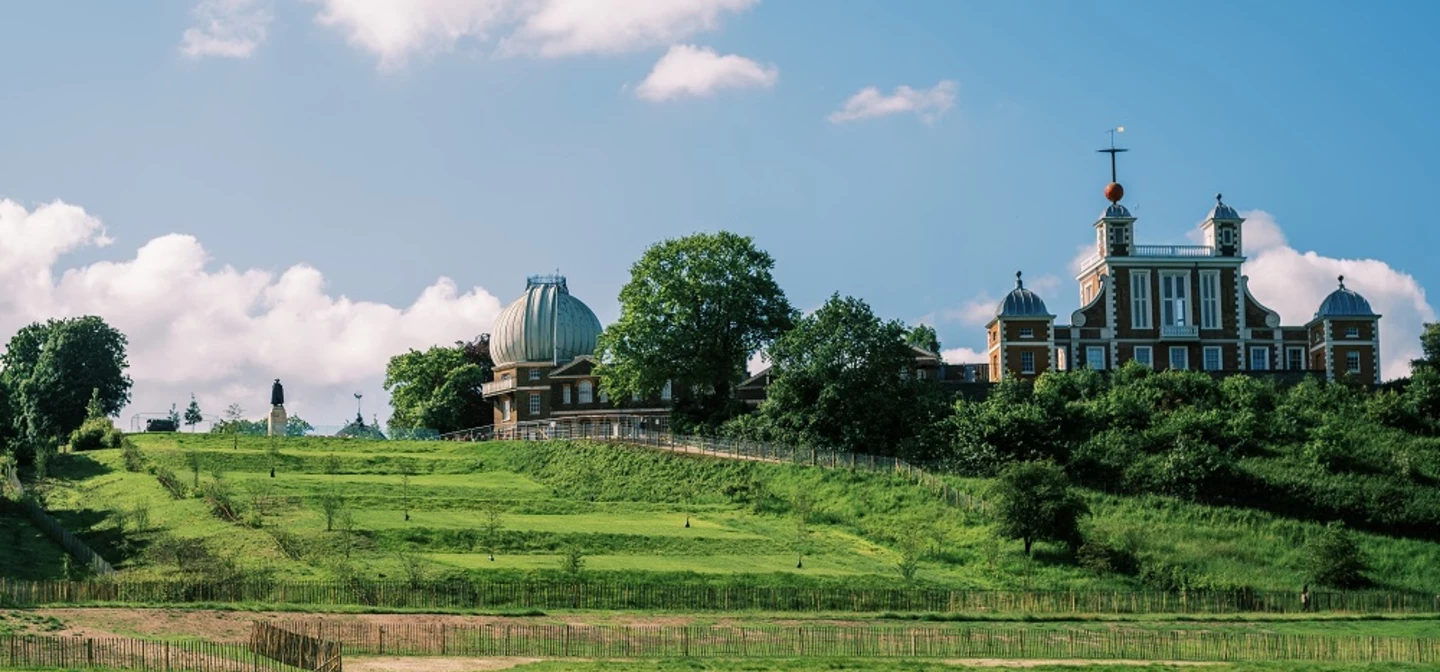 A view of the grand ascent in Greenwich Park on a sunny day with the Royal Observatory in the background.