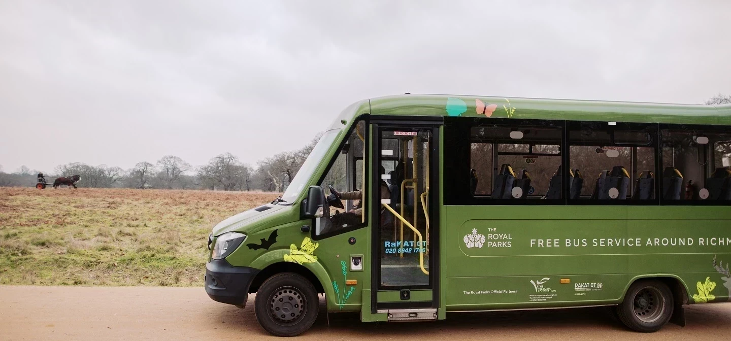 A side view of a green minibus going through Richmond Park
