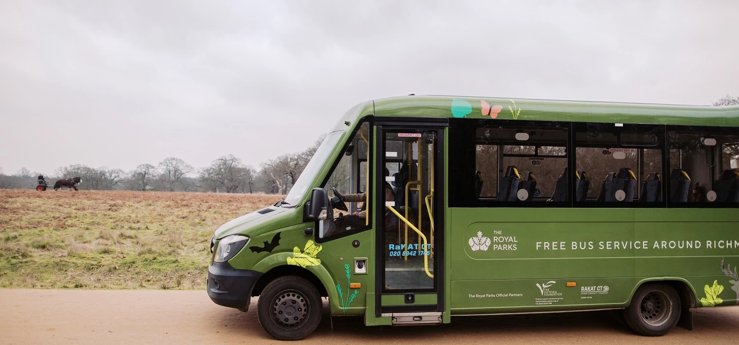 A side view of a green minibus going through Richmond Park