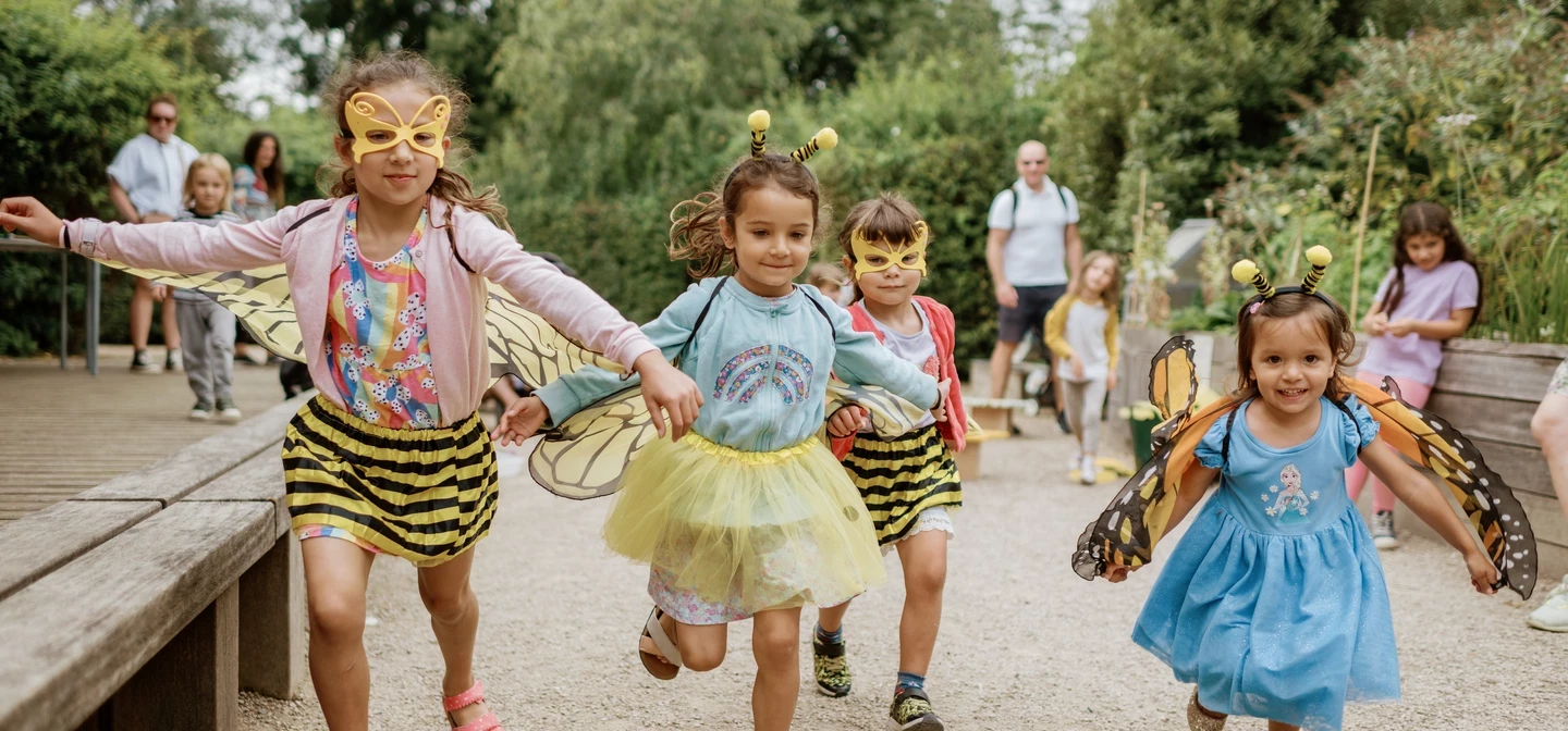 Image of children in bee costumes playing and running outdoors