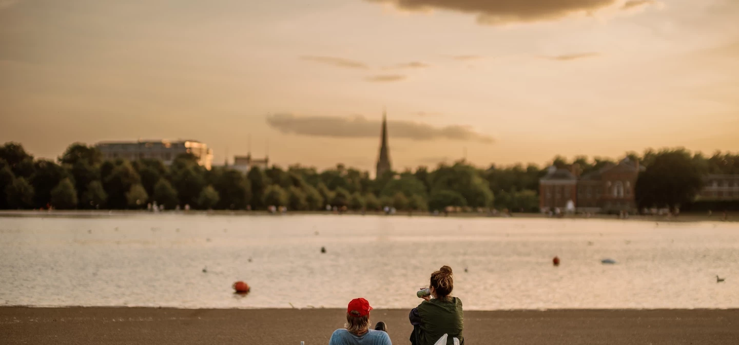 Image of two people sitting outdoors by a lake