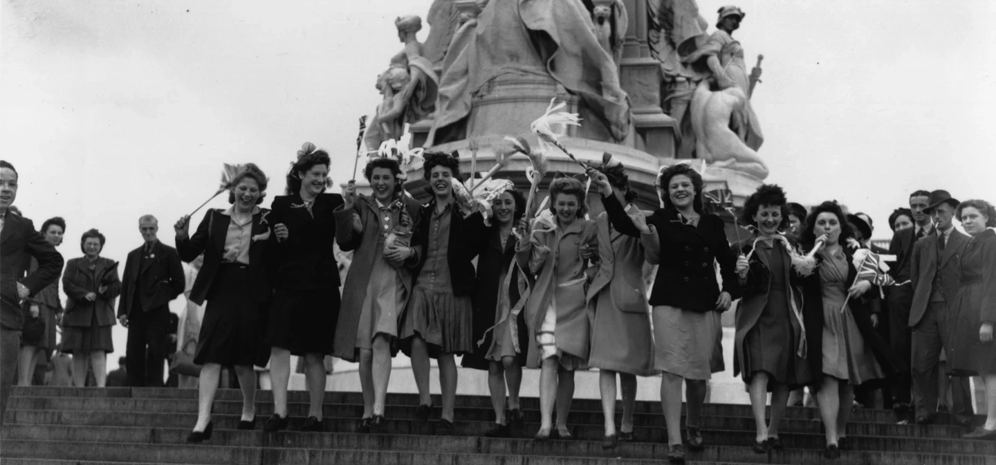 Women celebrate VE Day on the steps of the Queen Victoria Memorial outside Buckingham Palace 