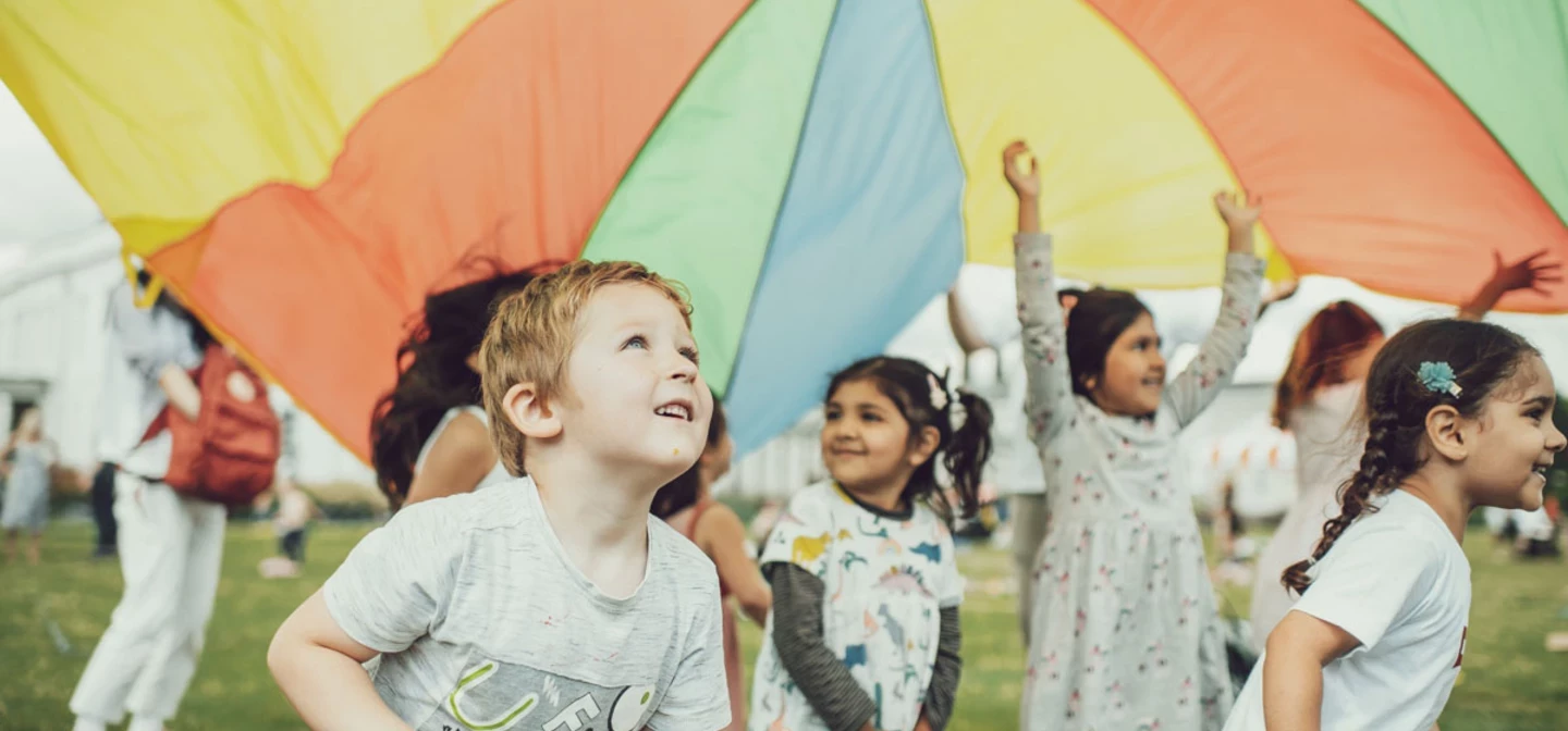 Young children playing with a play parachute