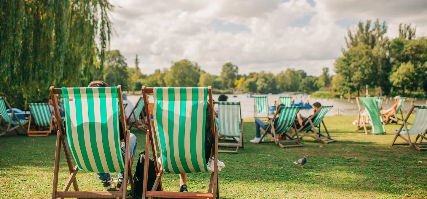 Green and white striped deck chairs in an outdoor, park setting.