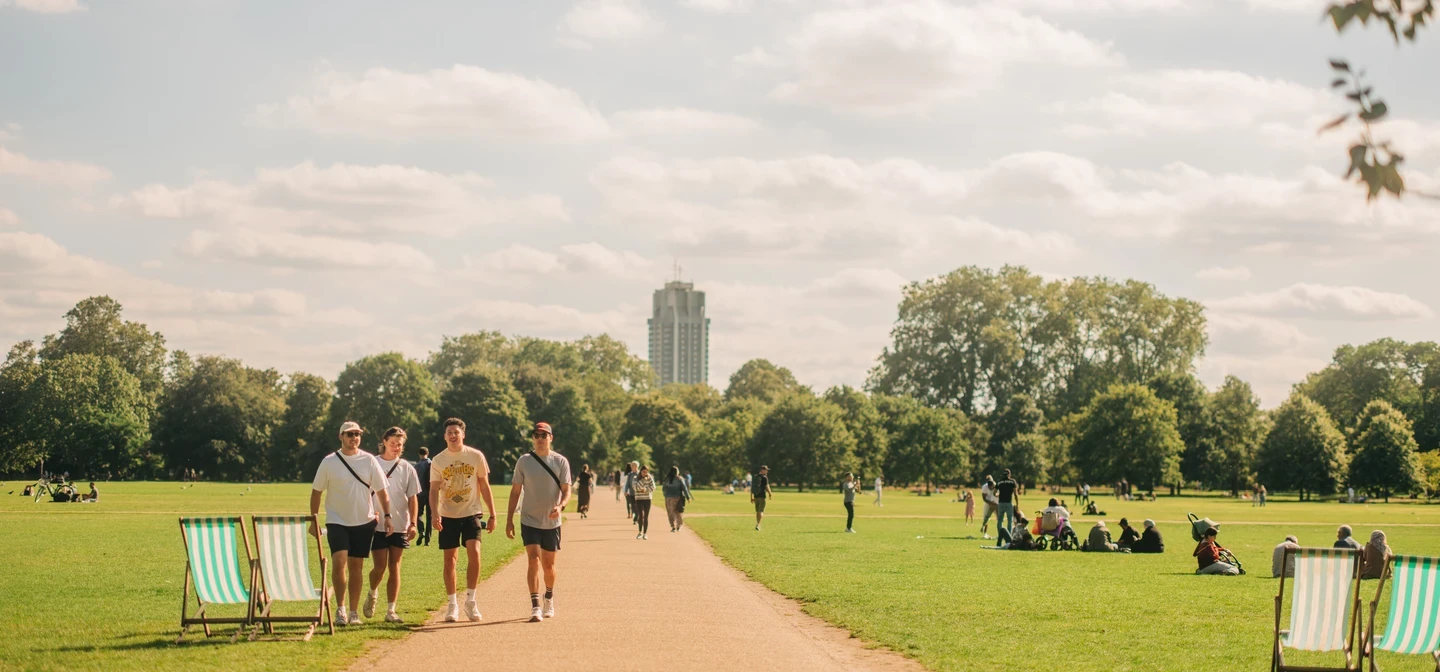 Image of people walking on a path that across a lush, green park. 