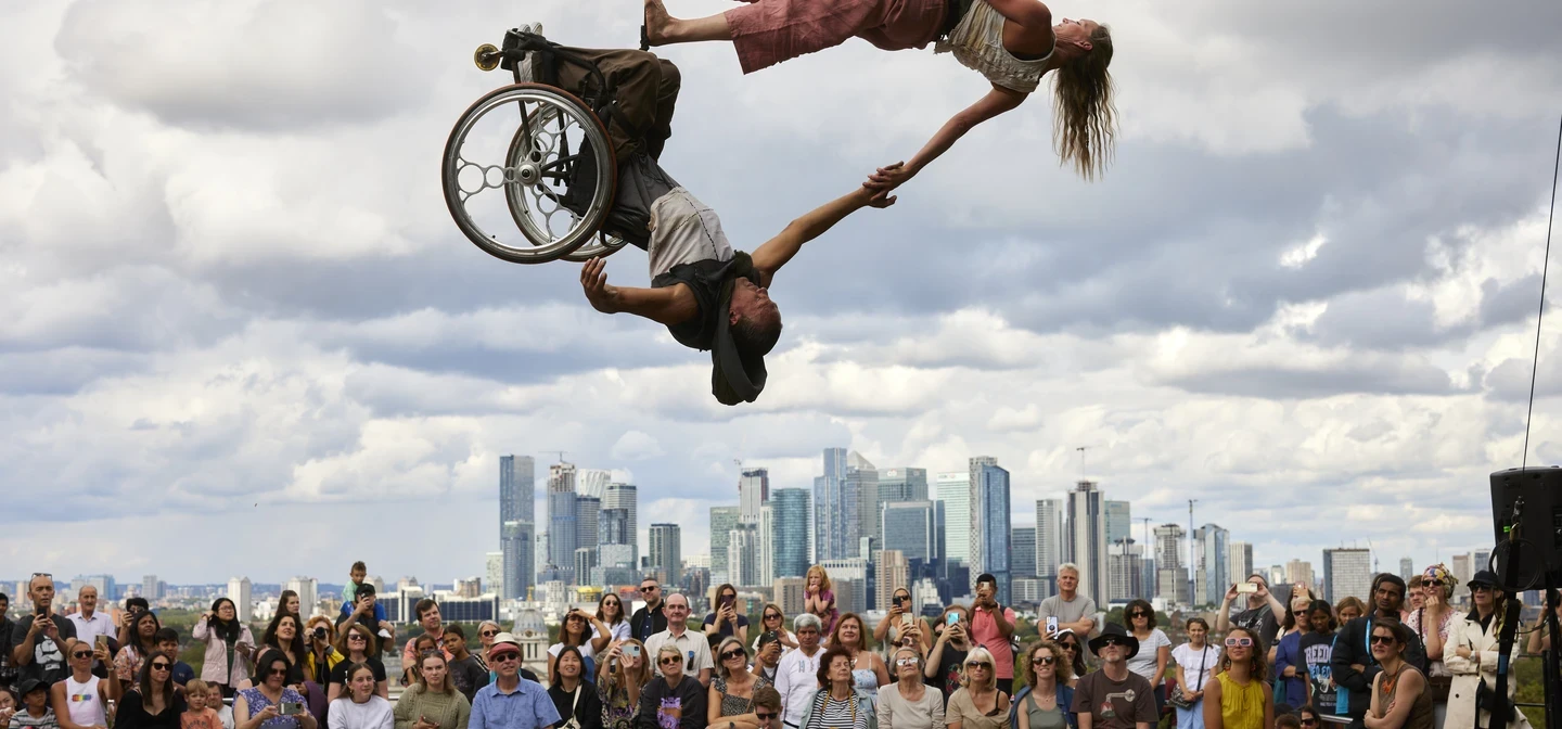 Image of circus performers on cycles against the backdrop of Greenwich Park.