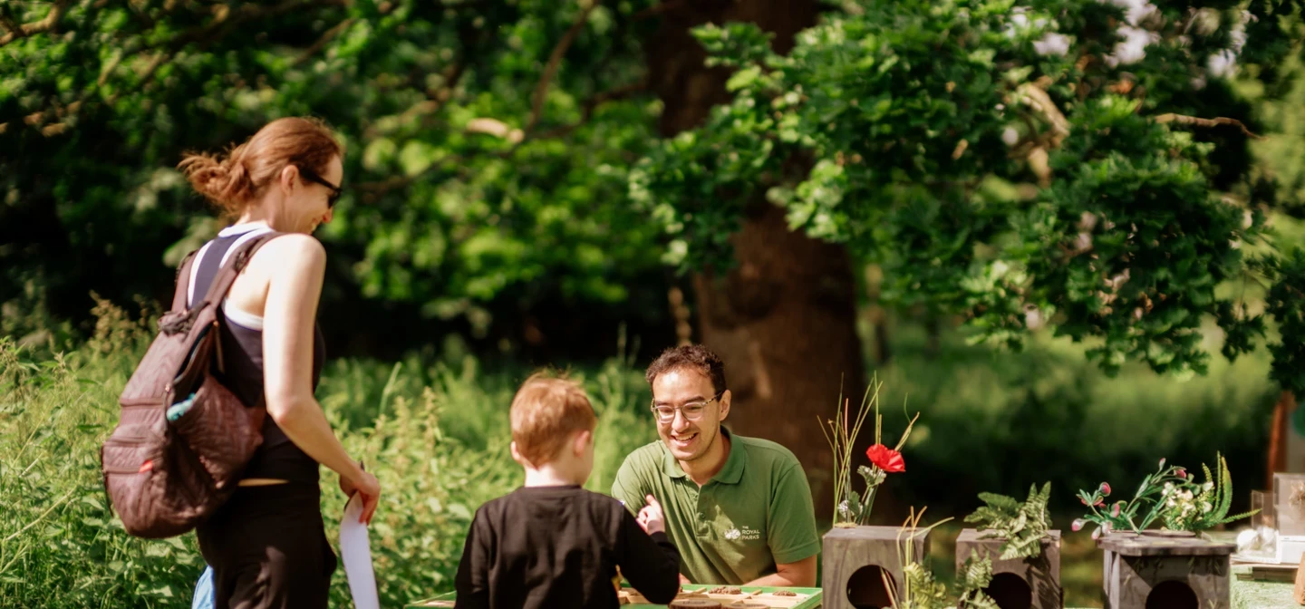 A mother and child playing a nature game at a table with a member of staff