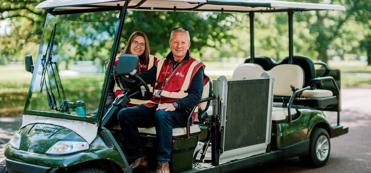 Two volunteers on a park mobility buggy