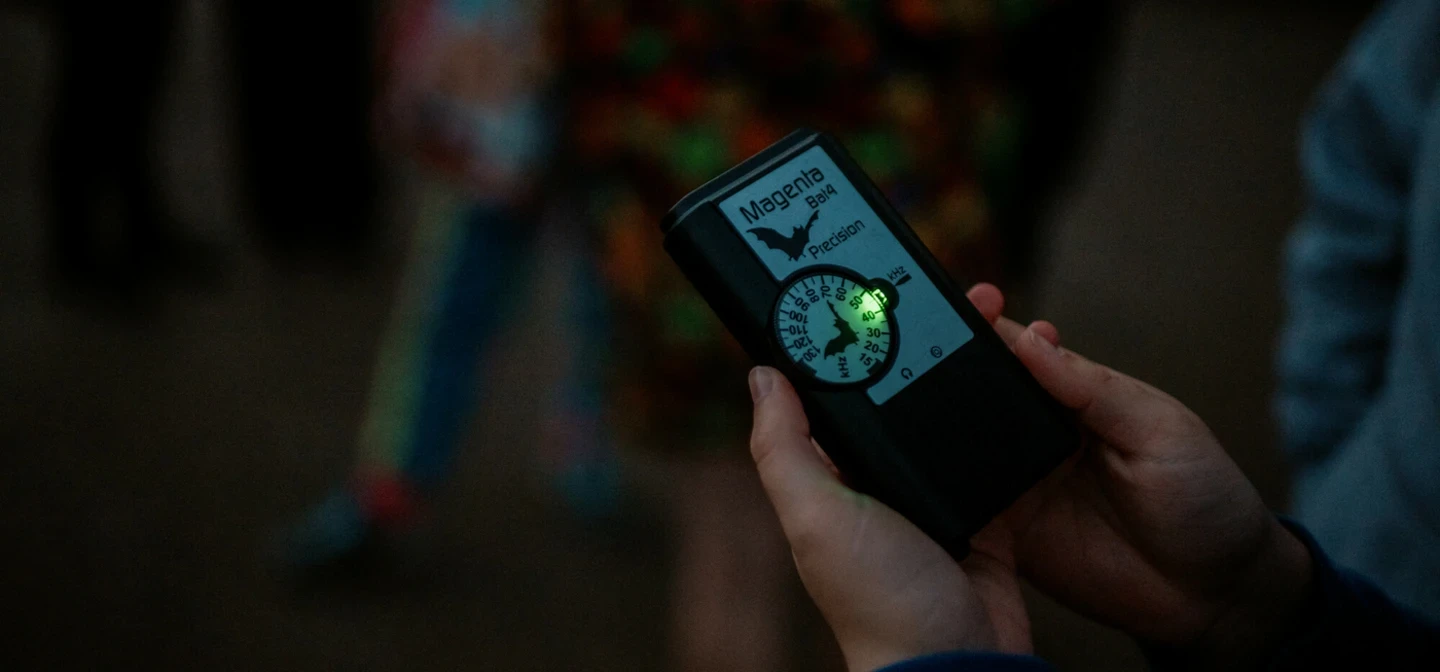 A Magenta bat detector is held at night a green light indicates it's on