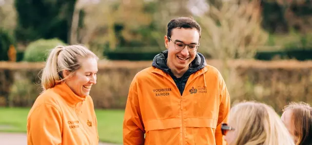 A photo showing two of our volunteer rangers in orange jackets speaking to park visitors 