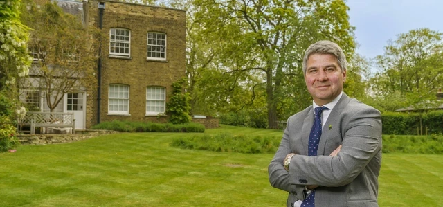 A man in a suit leaning against a bench