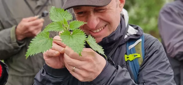 Man looking at a weed with a magnifying lens