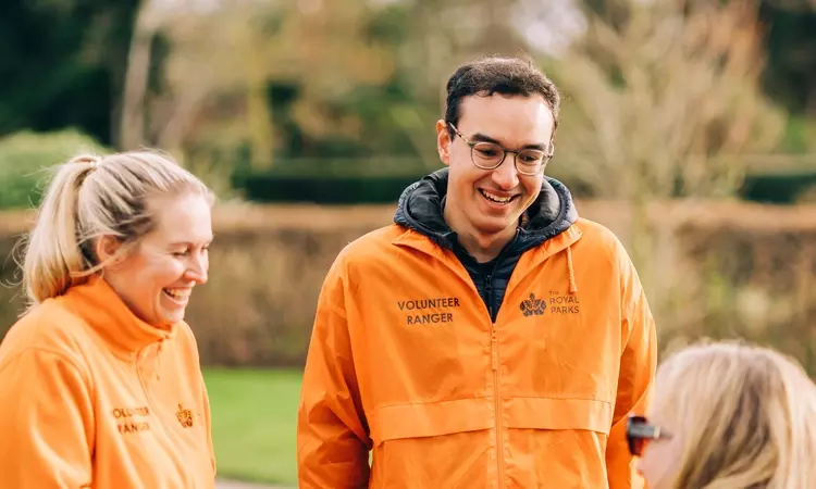 A photo showing two of our volunteer rangers in orange jackets speaking to park visitors 