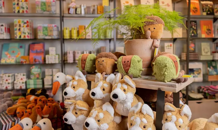 A shop display with piles of soft toy acorns, corgis, swans and robins