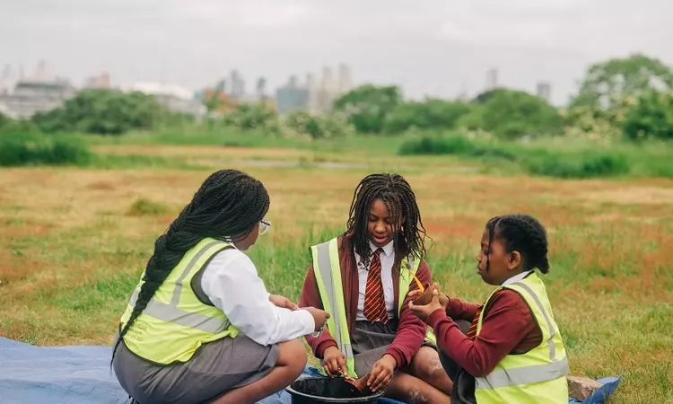 Three girls look over their finds with the view over London in the background