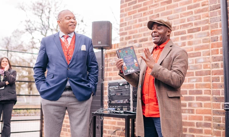 Wesley Kerr and Paterson Joseph are seen standing in front of the cafe building ask they speak at the opening event