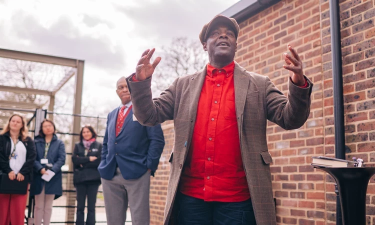 A shot taken from below looking up at Paterson joseph as he gesture with his arms in front of the cafe