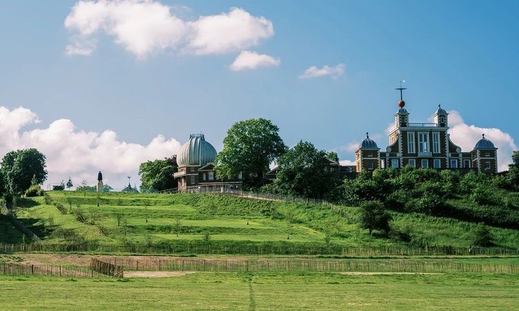 A view of the grand ascent in Greenwich Park on a sunny day with the Royal Observatory in the background.