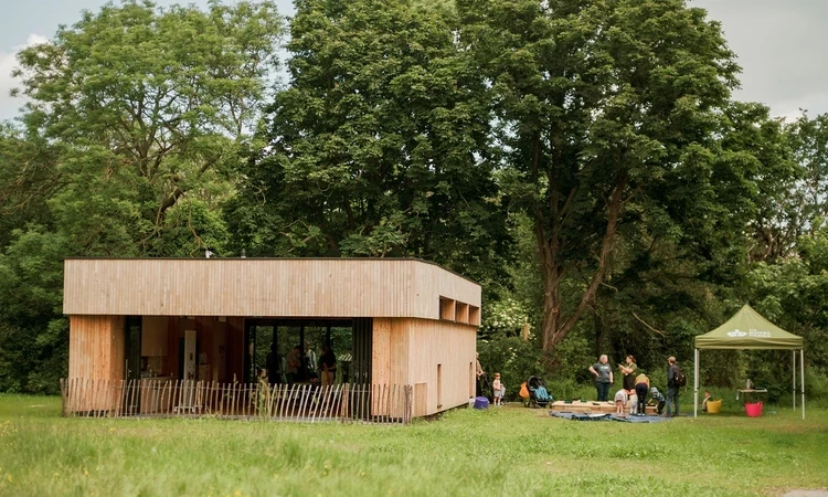 A view of the new Greenwich Park Learning Centre with a Royal Parks gazebo set up to the right of it.