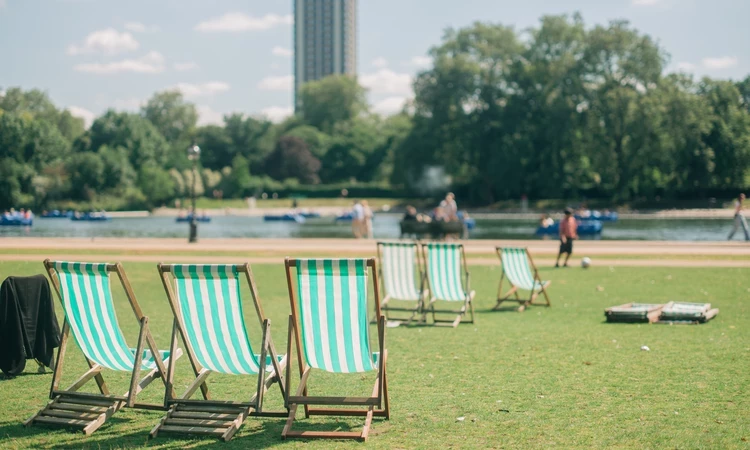 Three deck chairs on a green, grassy patch near a body of water