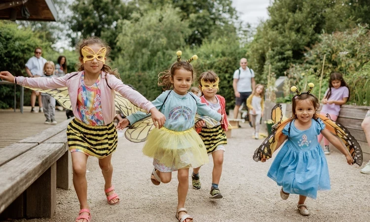Image of children in bee costumes playing and running outdoors