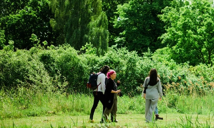 A small group of people walking beside the lake in The Regents Park