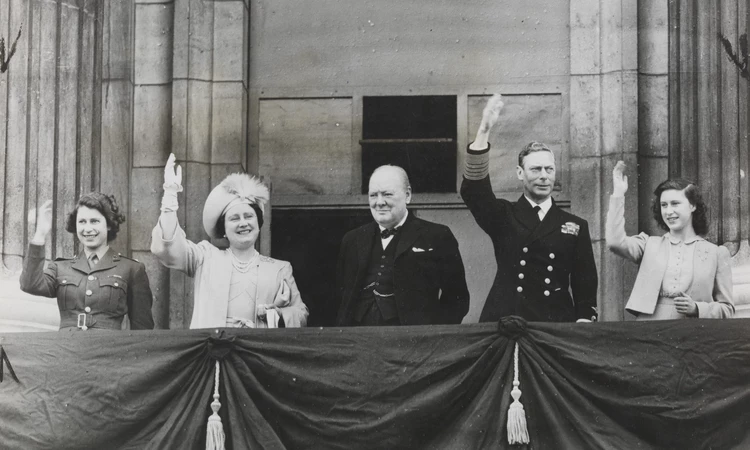 On VE Day, Princess Elizabeth, Queen Elizabeth, Winston Churchill, King George VI and Princess Margaret waves to crowds from Buckingham Palace 