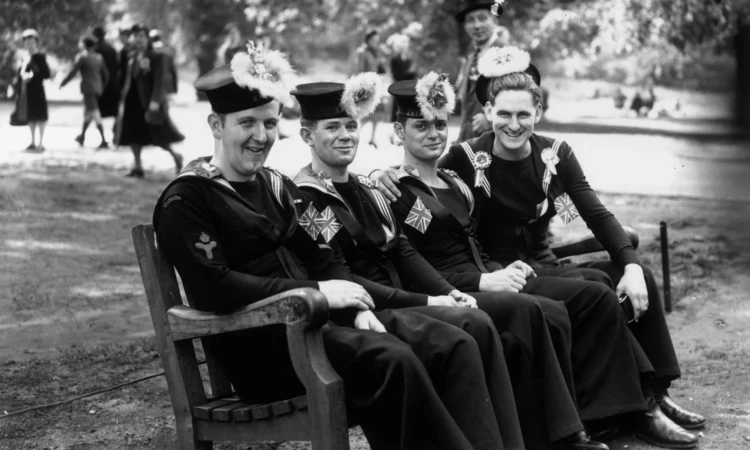 Canadian sailors sit on a bench in the park during the VE day celebrations in 1945 