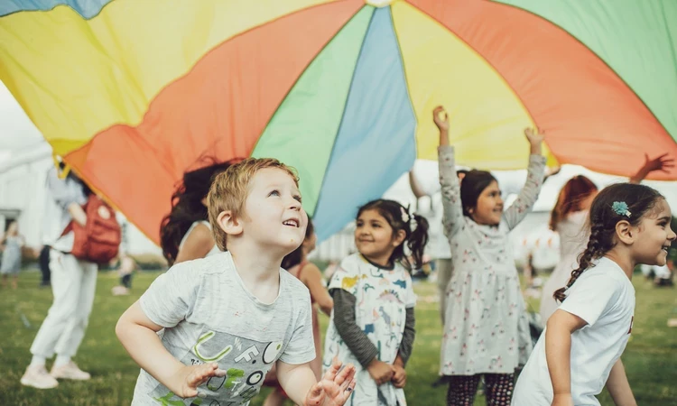 Young children playing with a play parachute