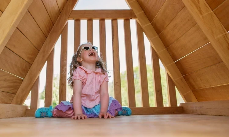 Young girl laughing under a play shelter