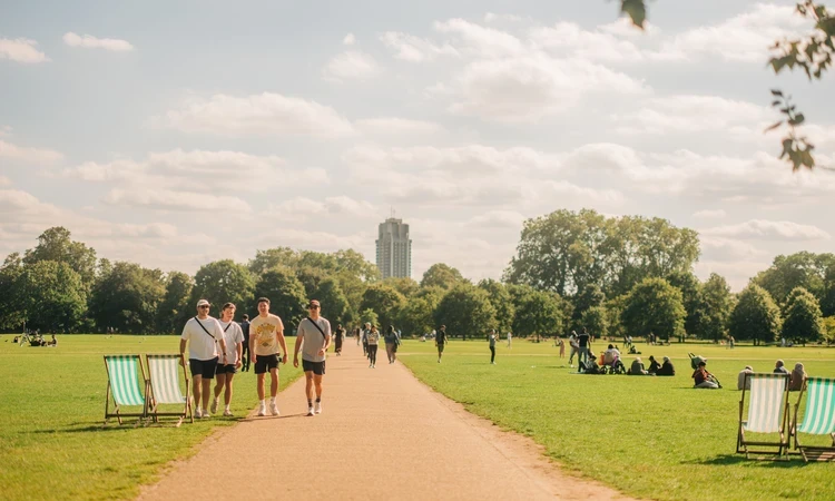 Image of people walking on a path that across a lush, green park. 