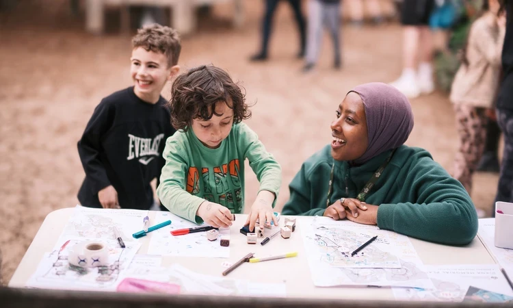 A Royal Parks Play Officer drawing with youngsters