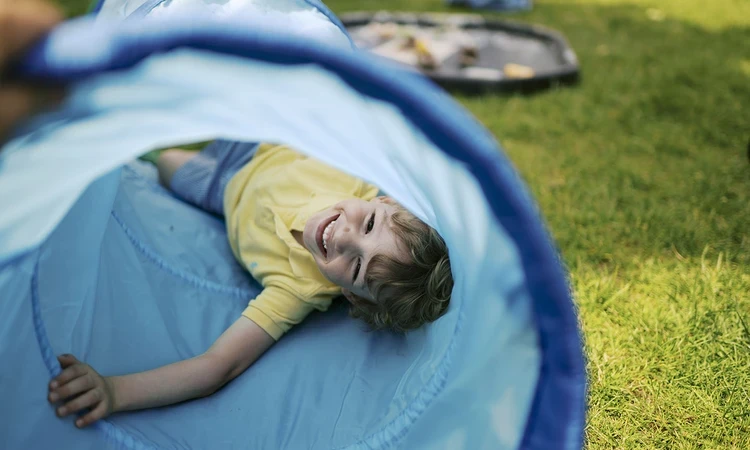 Young boy laying in a play tunnel