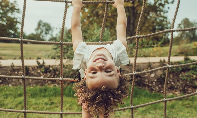 Young girl hanging upside-down on a rope net