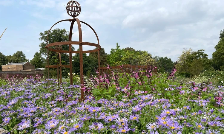 Globe-shaped garden feature nestled among a sea of pink and purple flowers.